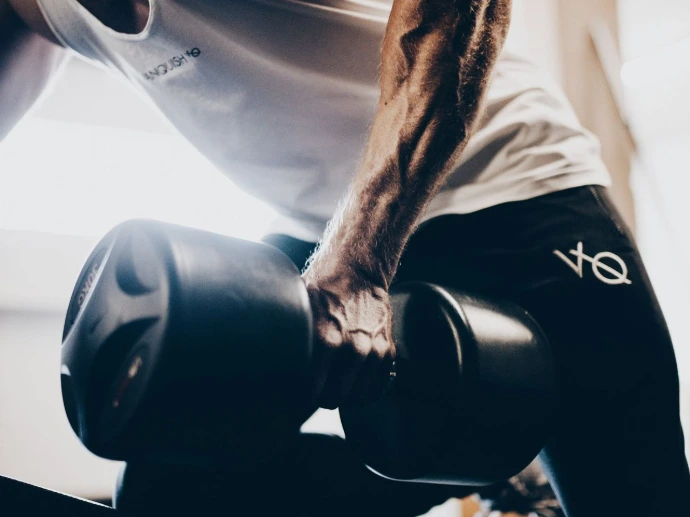man in blue tank top and black shorts holding black dumbbell